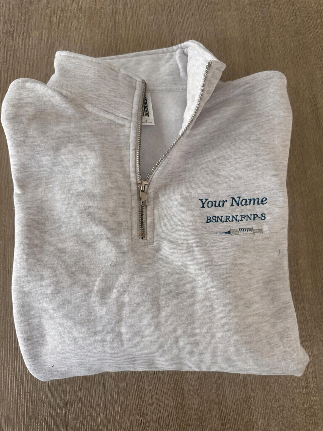Personalized nurse quarter-zip with embroidered name, credentials, and syringe